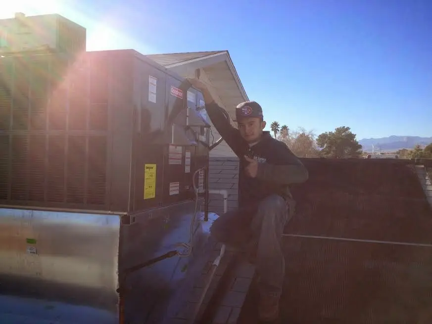 HVAC technician performing AC Tune-Up on a rooftop unit in Wimauma